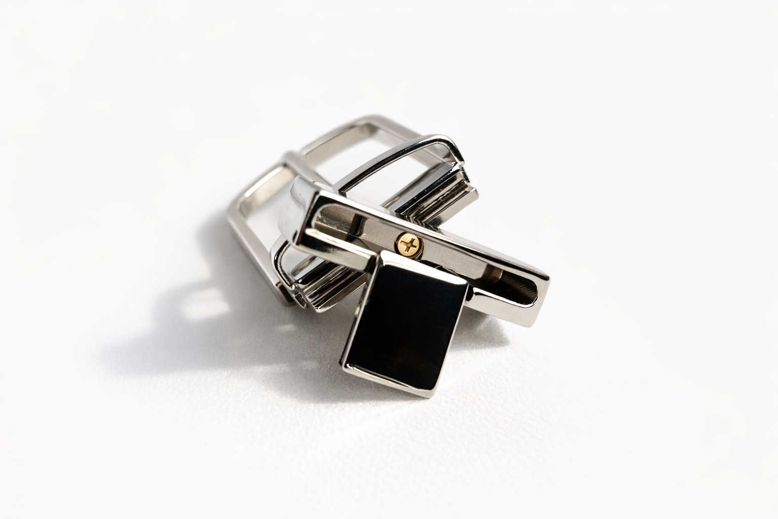 attacco-per-fibbia-reversibile Attacco per fibbia reversibile in metallo lucido colore argento, con meccanismo a perno e vite centrale visibile, fotografato su sfondo bianco con ombra morbida.