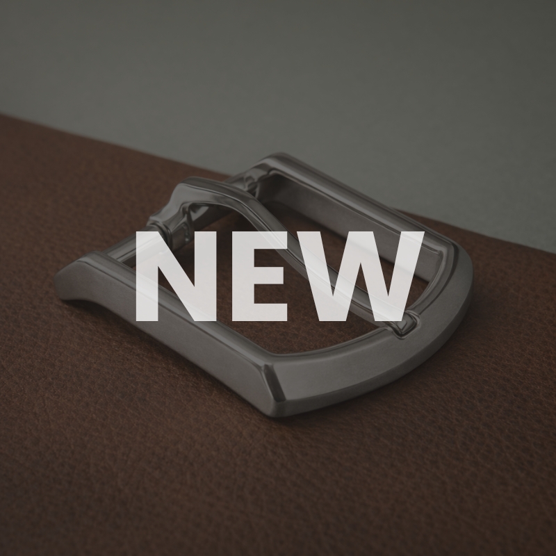 fibbia in ottone con ardiglione speciale poggiata su un tessuto in pelle marrone